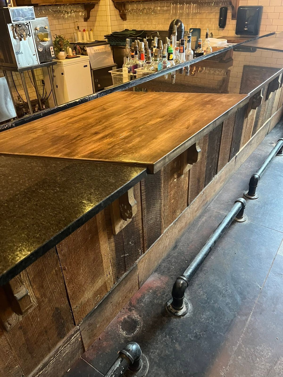Restaurant bar with reclaimed wood front, wood and granite tops and pipe foot rail