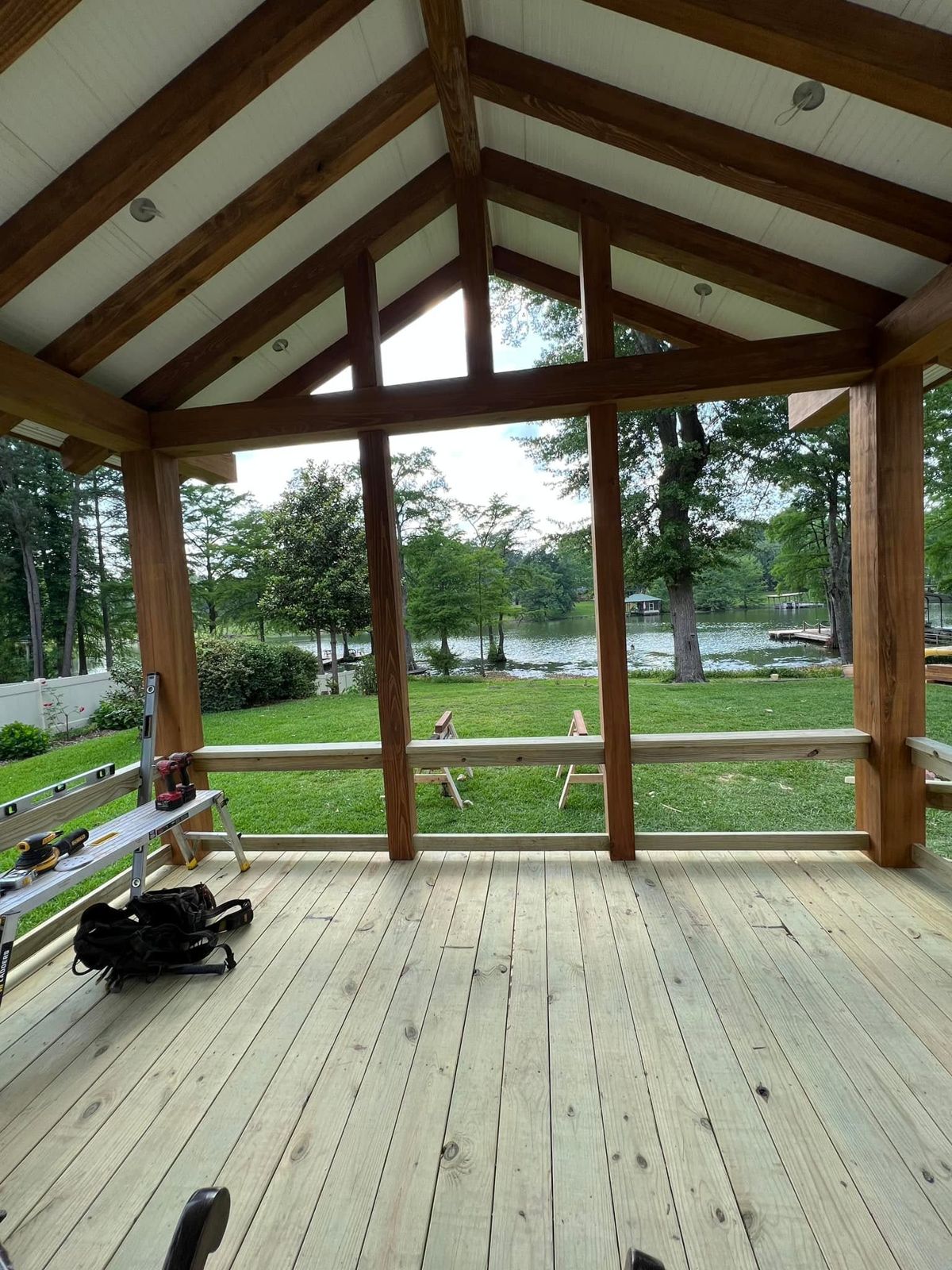 Timber-framed covered porch with vaulted beadboard ceiling overlooking a lake